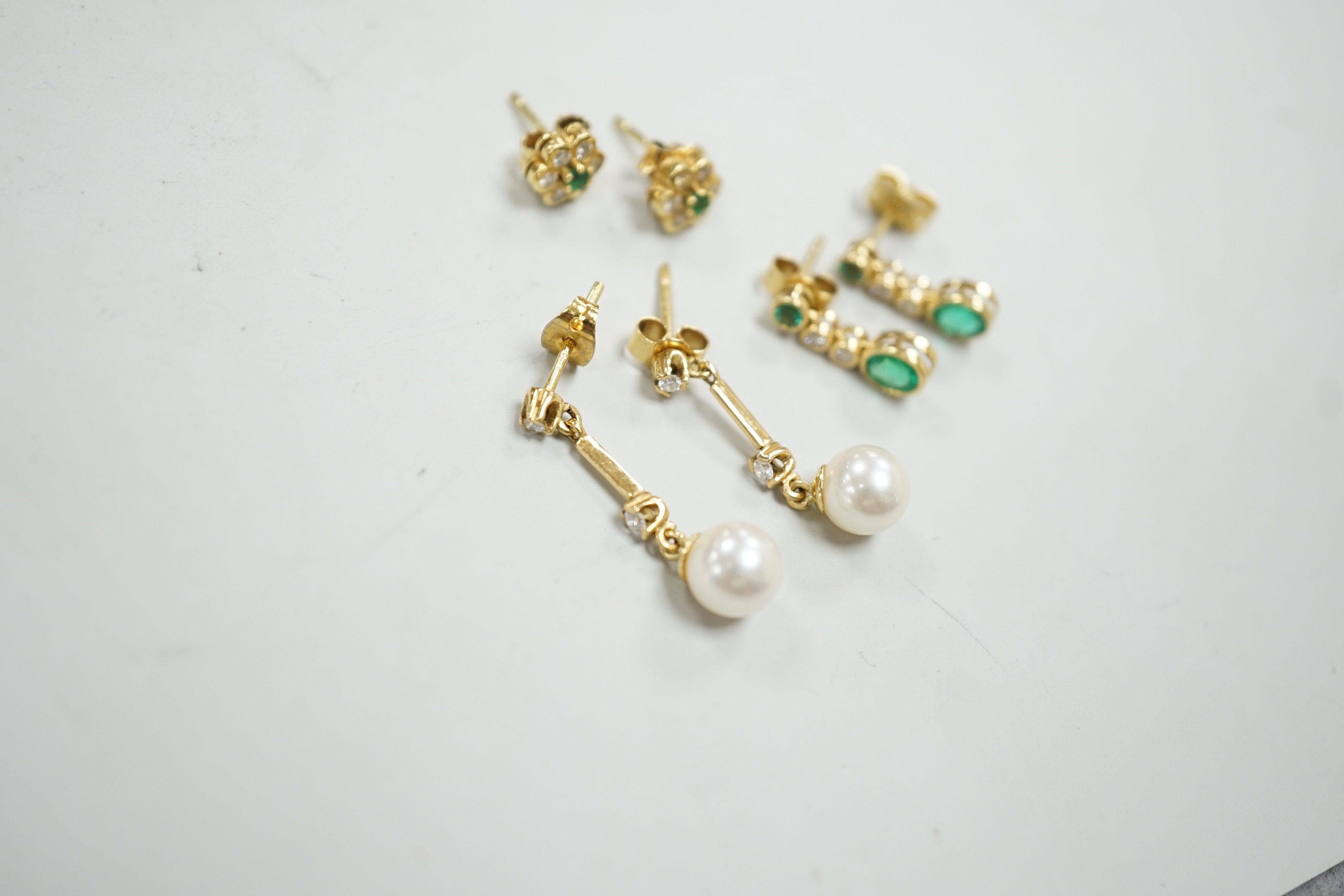 Two modern pairs of 18ct gold, emerald and diamond set ear studs and a pair of 18ct gold, cultured pearl and diamond set ear studs, gross weight 7 grams.